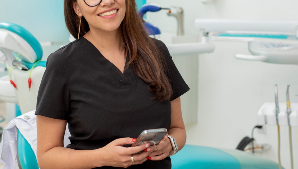 A happy dentist holding the OrthoPhoto dental recordkeeping app